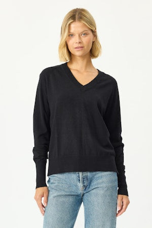 Woman wearing a black sweater and light blue jeans on a white background
