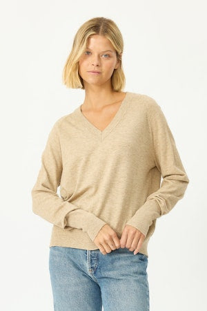 Woman wearing a beige sweater and blue jeans on a white background