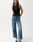 Woman wearing a black sleeveless top and blue jeans on a white background