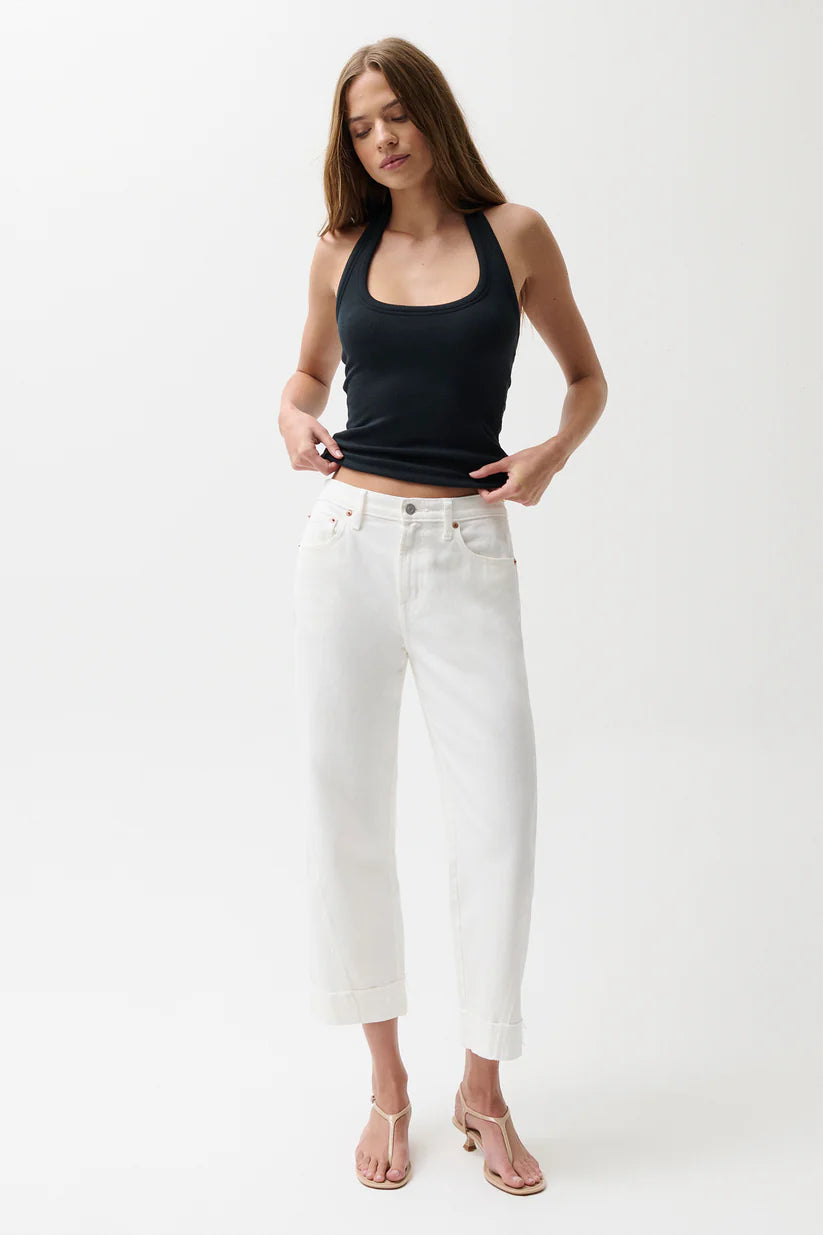 Woman wearing a black tank top and white pants on a white background