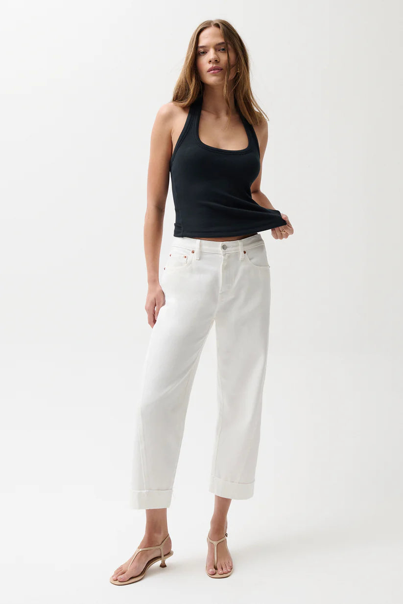 Woman wearing a black tank top and white pants on a white background