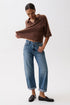 Person wearing a brown poncho and blue jeans on a white background