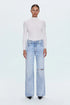 Person wearing a white turtleneck and light blue jeans on a white background
