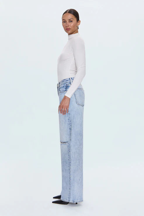 Woman wearing a white turtleneck and light blue jeans on a white background
