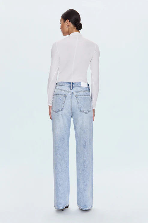 Person wearing light blue jeans and a white top on a white background