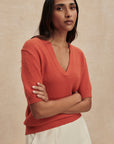 Woman wearing a coral sweater against a beige background