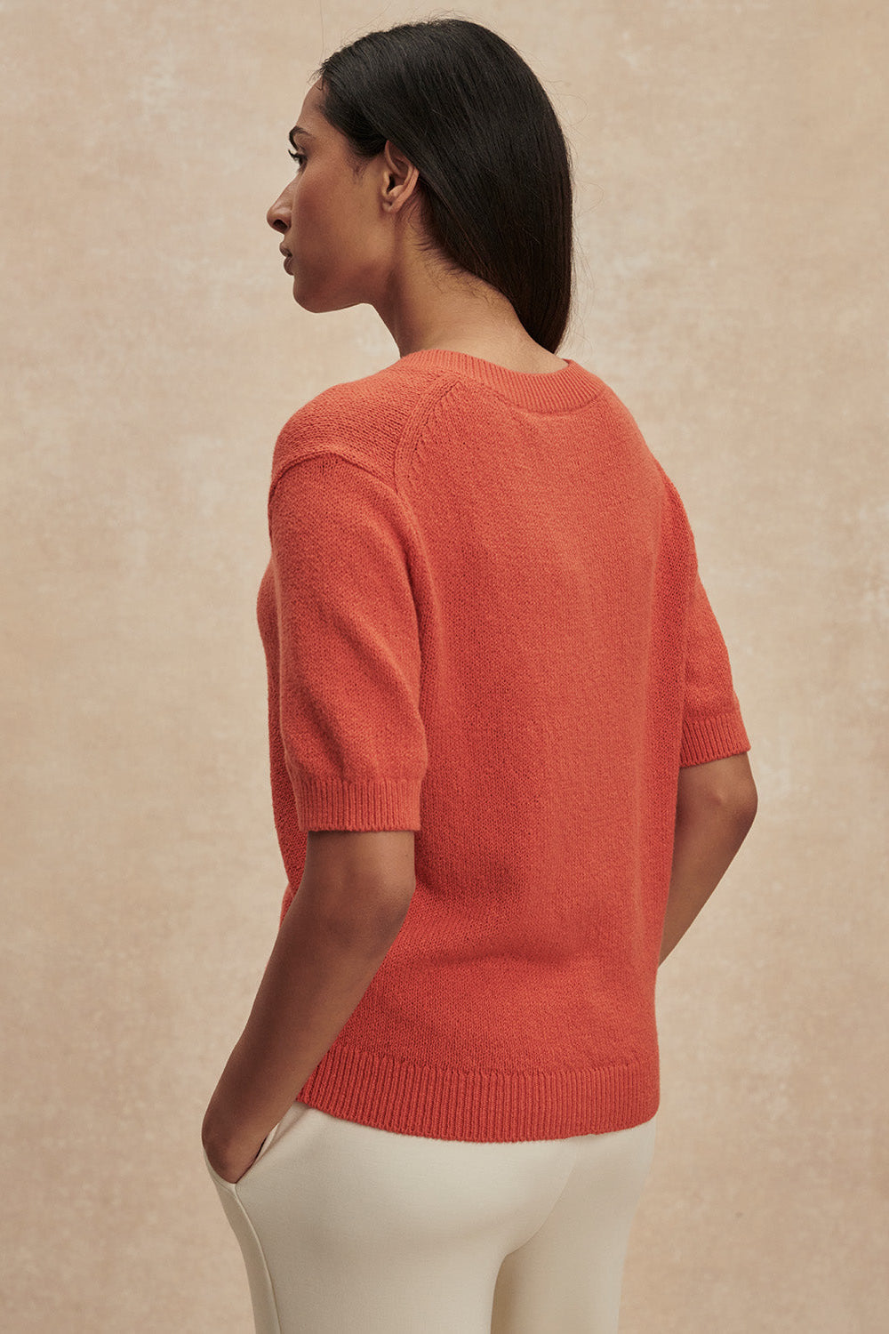 Woman wearing a red sweater against a beige background