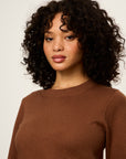 Woman wearing a brown sweater against a plain background