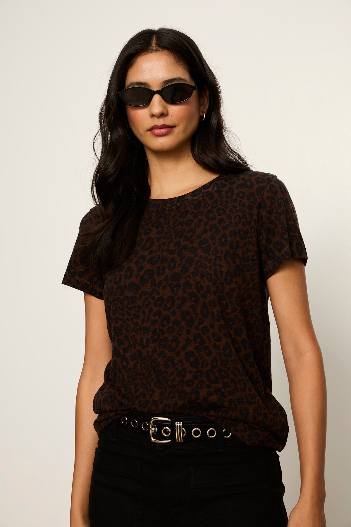 Woman wearing a dark patterned top and sunglasses against a plain background
