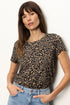 Woman wearing a leopard print shirt and blue jeans against a white background
