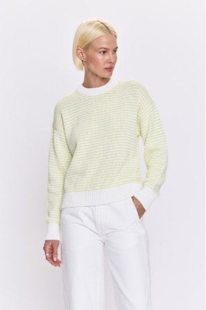 Person wearing a light green sweater and white pants on a white background