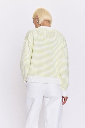 Person wearing a light green striped sweater and white pants on a white background