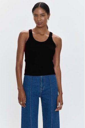 Woman wearing a black tank top and blue jeans on a white background