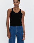 Woman wearing a black tank top and blue jeans on a white background