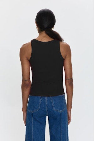 Person wearing a black tank top and blue jeans on a white background
