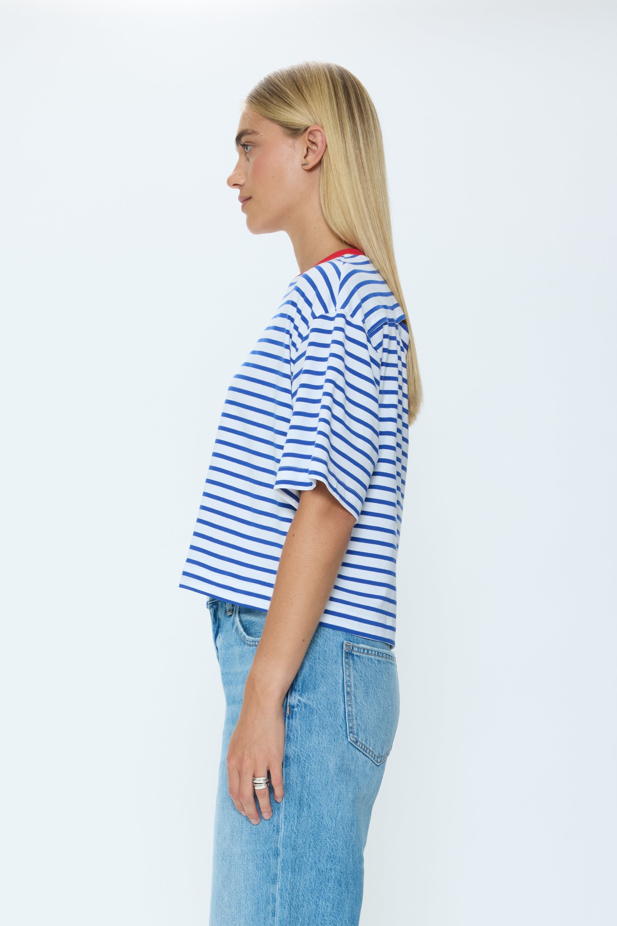 Person wearing a blue and white striped shirt and light blue jeans on a white background