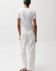 Person wearing a white t-shirt and white pants with a green cap on a white background