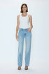 Woman wearing a white tank top and light blue jeans on a white background