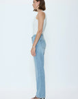 Woman wearing a white sleeveless top and light blue jeans on a white background