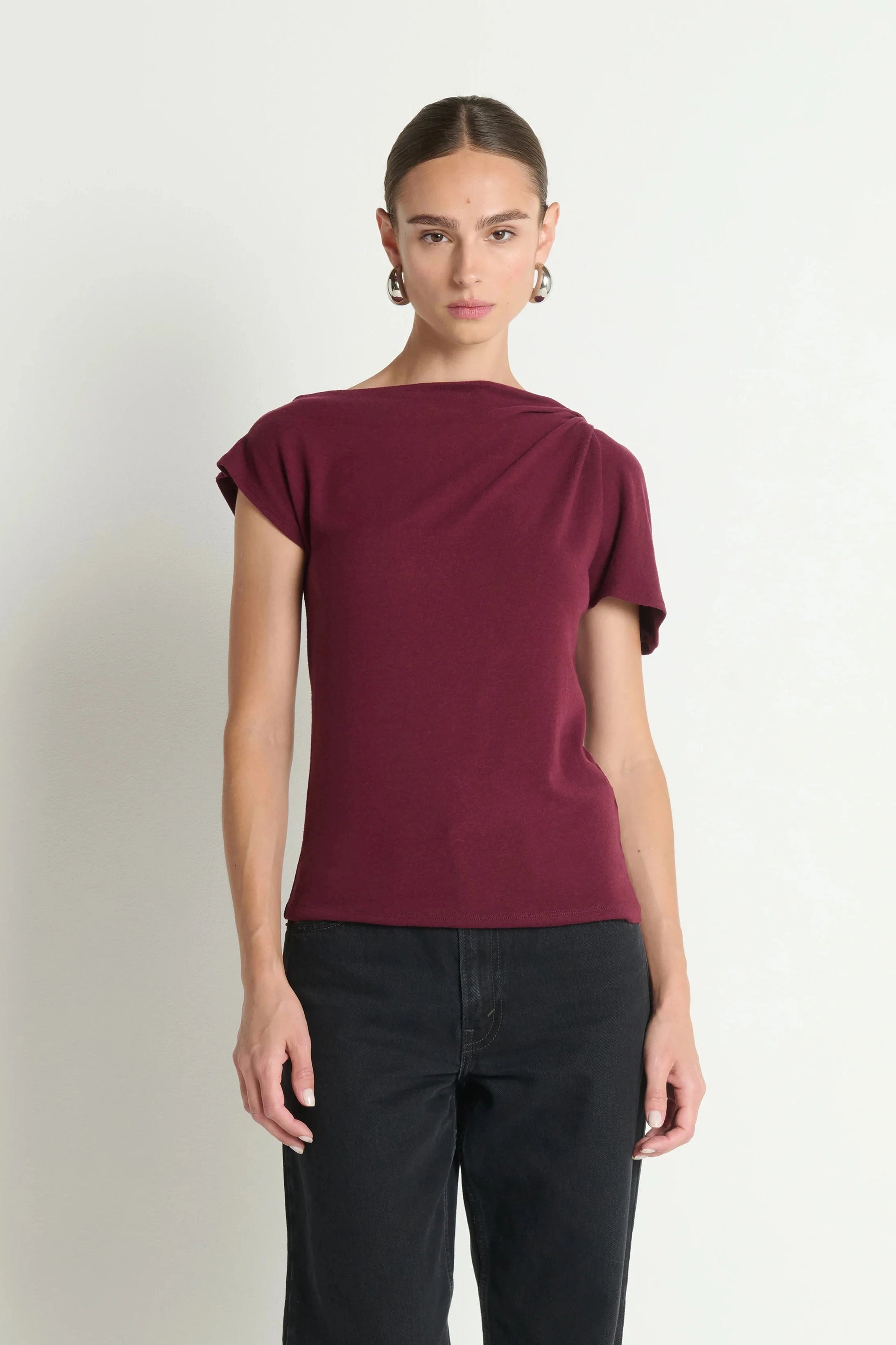 Woman wearing a burgundy top and black pants on a white background