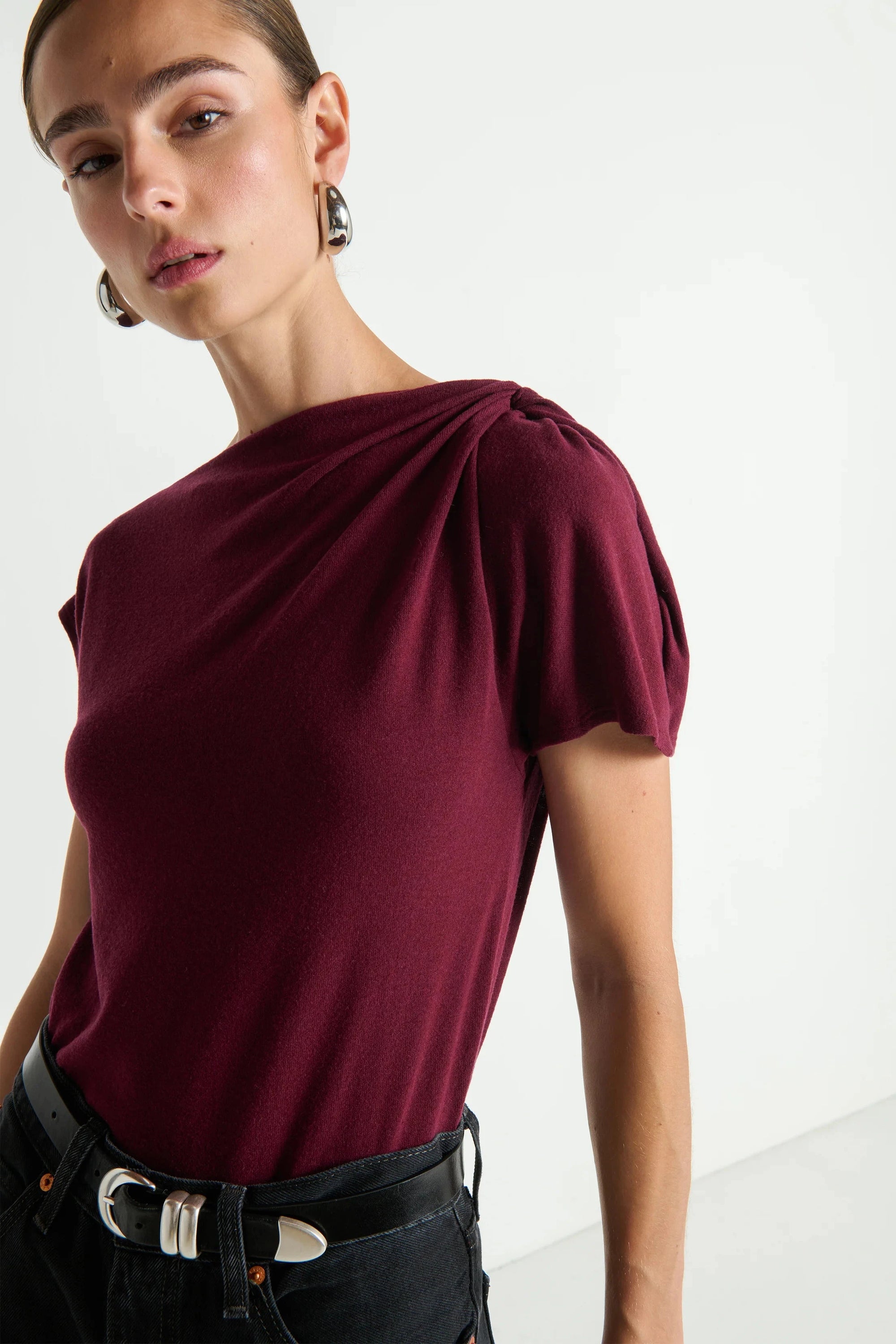 Woman wearing a burgundy top with a plain background