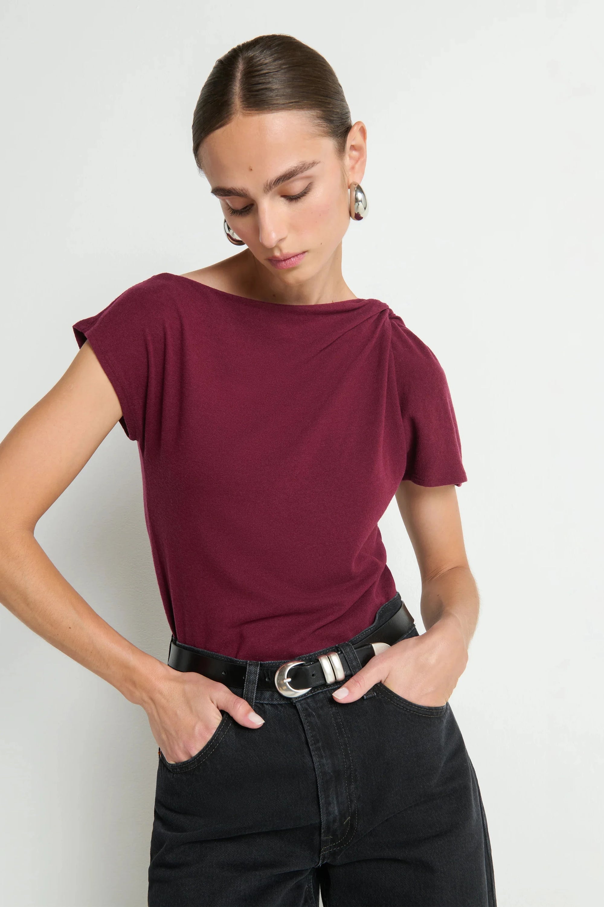 Woman wearing a burgundy top and black pants against a white background