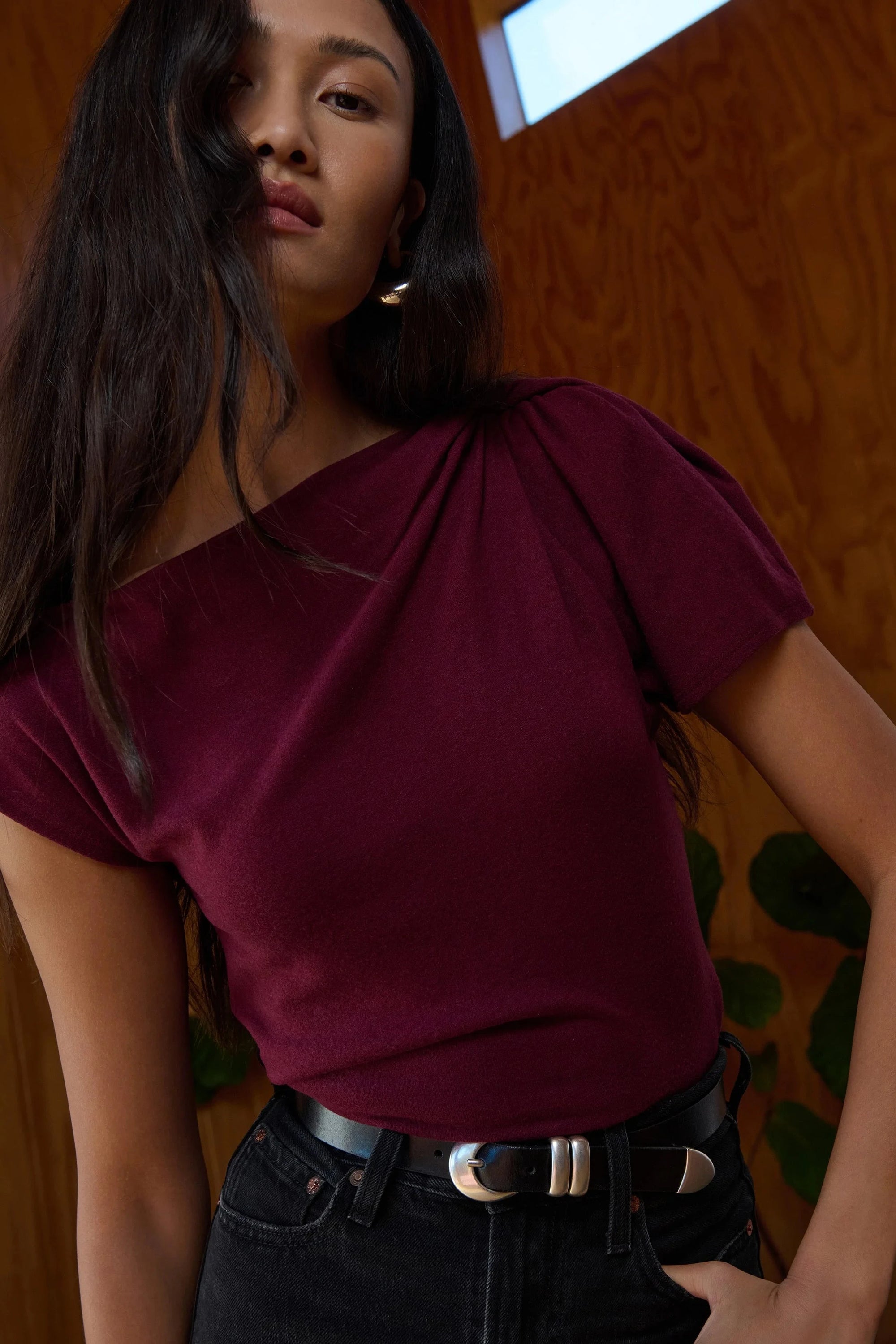 Woman wearing a burgundy top with a wooden wall background