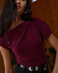 Woman wearing a burgundy top with a wooden wall background