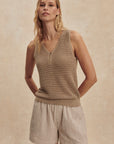 Woman wearing a beige sleeveless top and shorts against a beige background