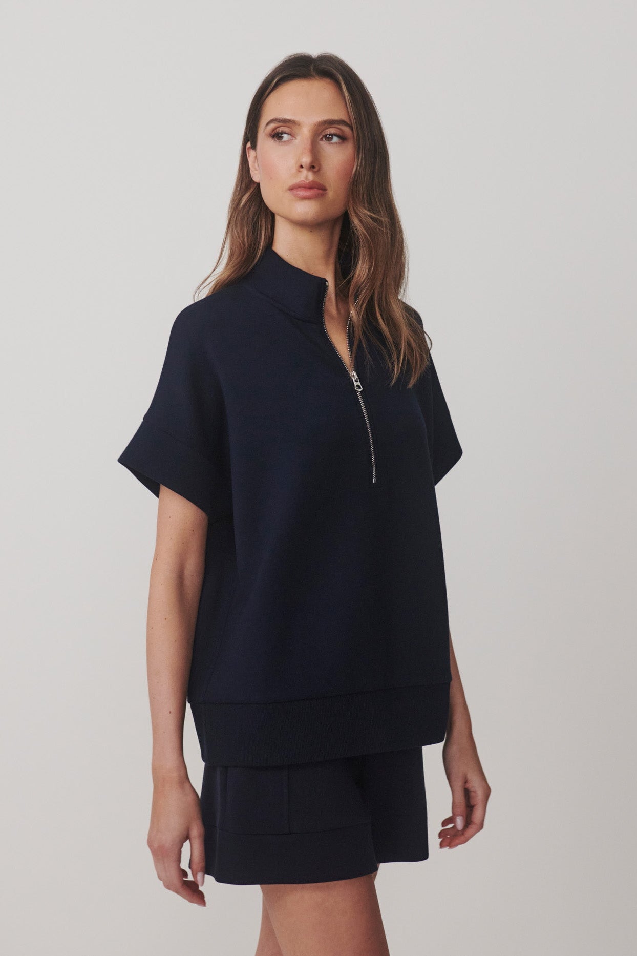 Woman wearing a navy blue outfit with a plain background