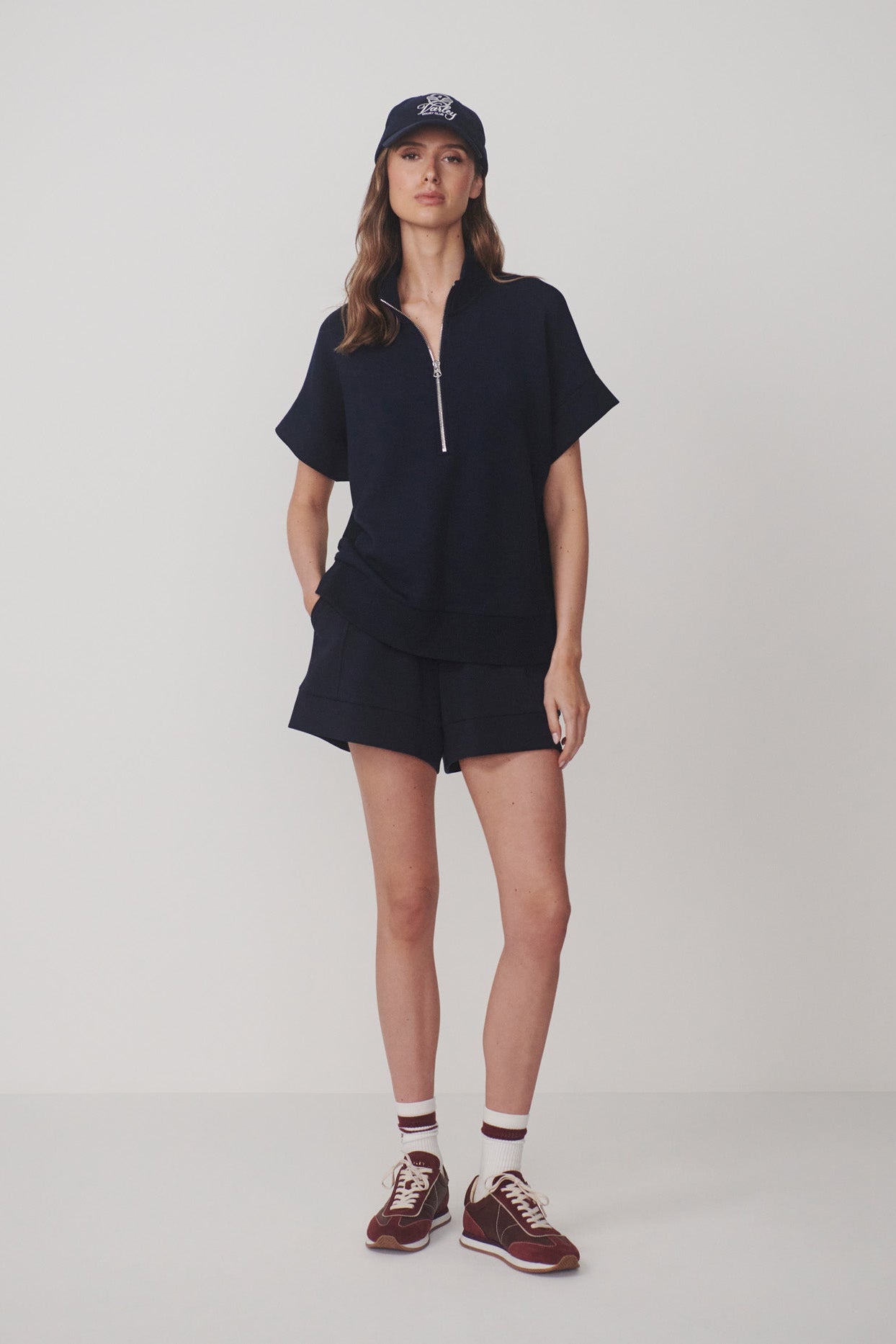 Person wearing a navy outfit with a cap on a white background