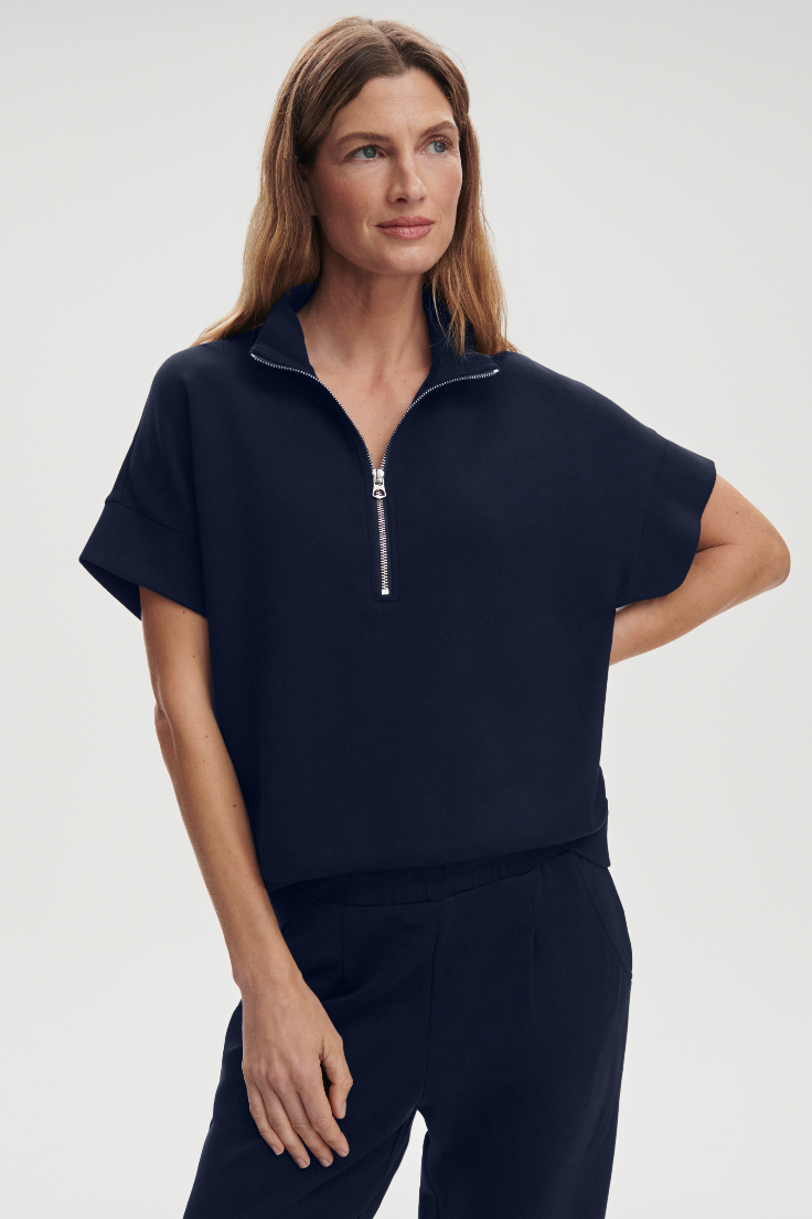 Woman wearing a navy blue zip-up top on a light gray background