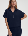 Woman wearing a navy blue zip-up top on a light gray background