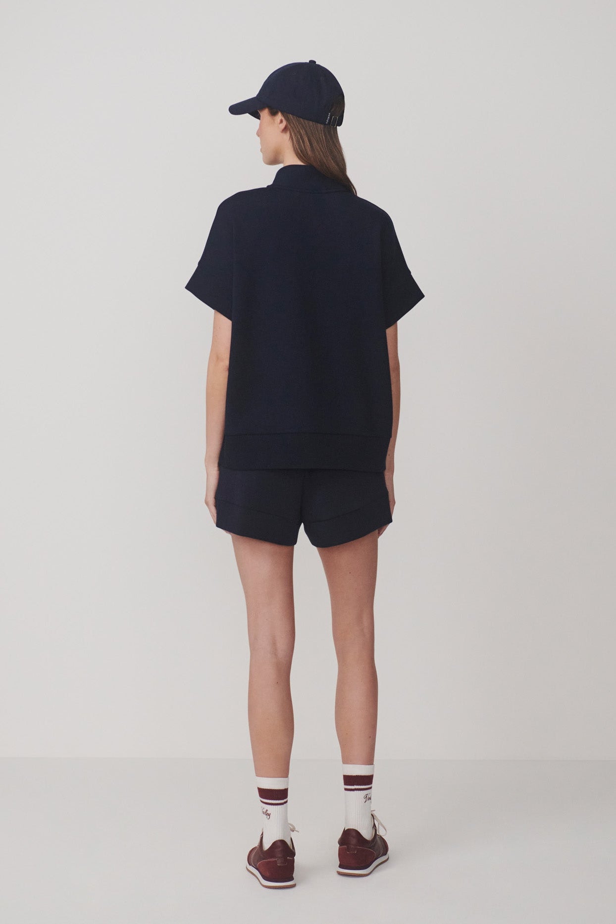 Person wearing a navy outfit with a cap on a white background