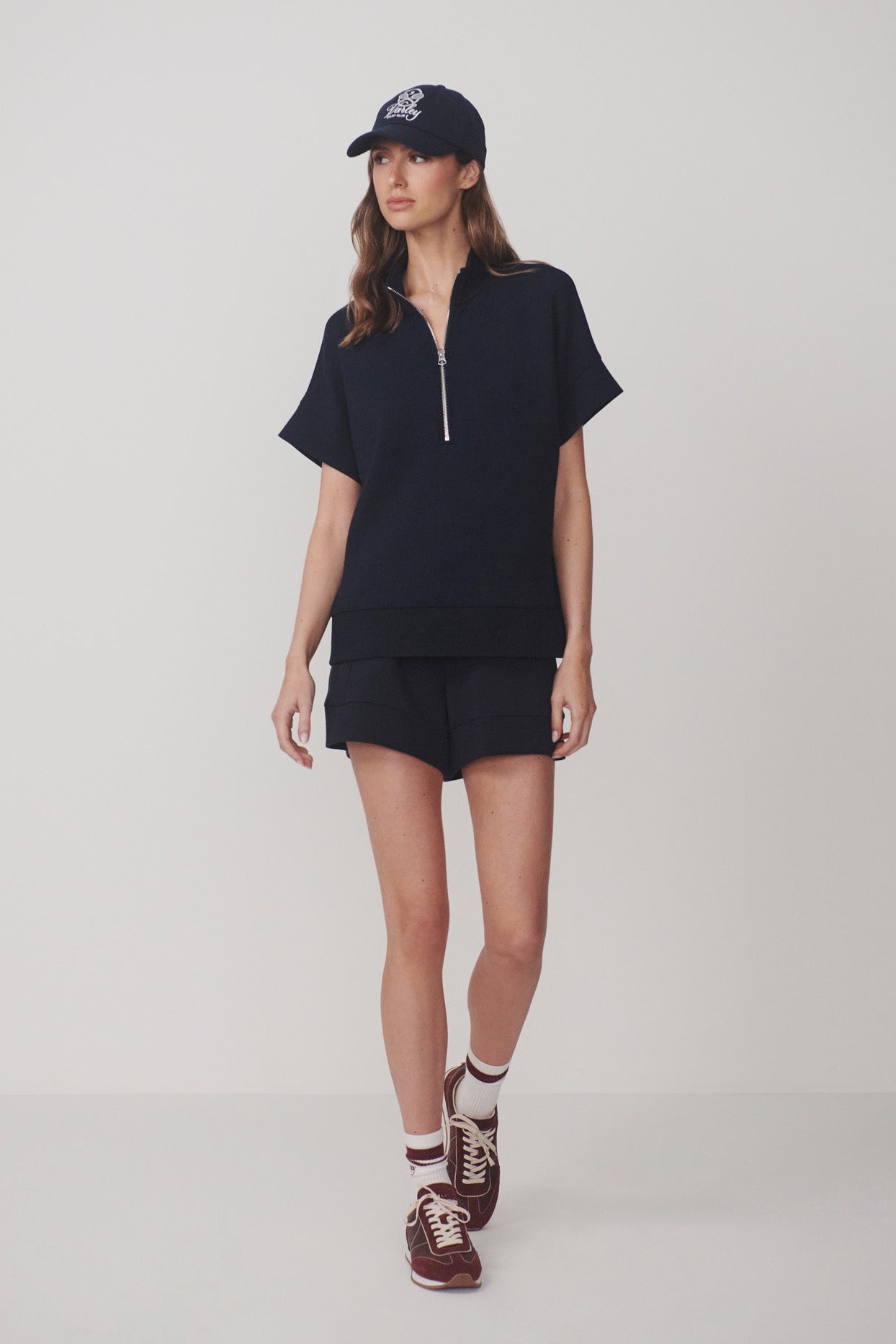 Woman wearing a black outfit with a cap on a white background