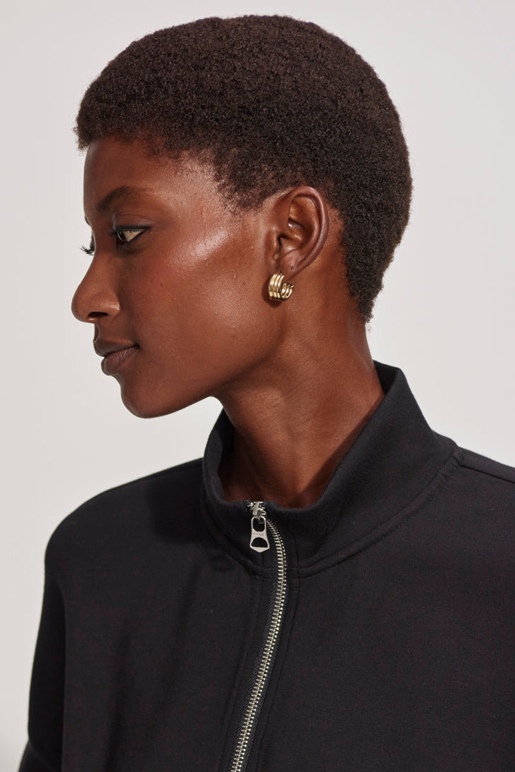 Woman wearing a black jacket with a zipper, side view