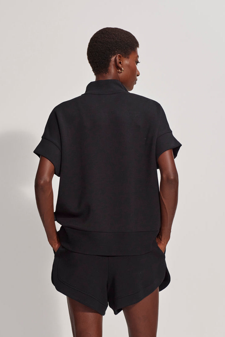 Person wearing a black outfit on a plain background