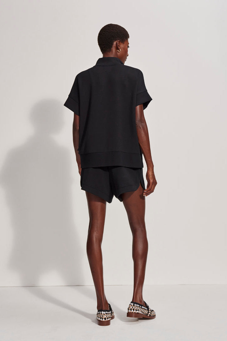 Person wearing a black outfit standing against a white background