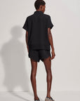 Person wearing a black outfit standing against a white background