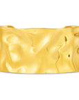 Gold cuff bracelet with a hammered texture on a white background