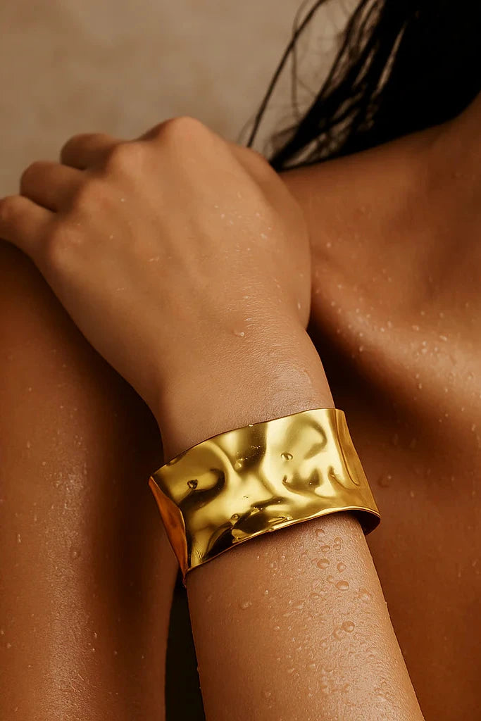 Gold bracelet on a person's wrist with a blurred background