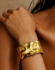 Gold bracelet on a person's wrist with a blurred background