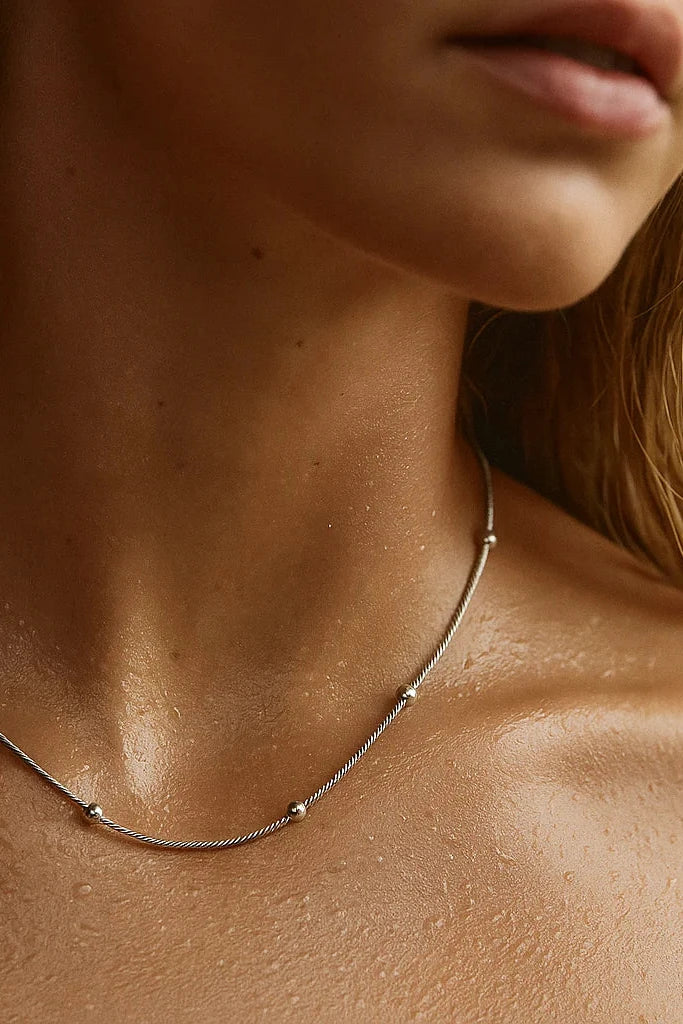 Close-up of a person wearing a delicate necklace with a blurred background