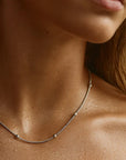 Close-up of a person wearing a delicate necklace with a blurred background