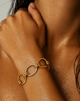 Close-up of a person wearing a gold chain bracelet on a sunlit skin background