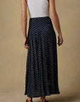 Person wearing a black patterned skirt and white top on a beige background