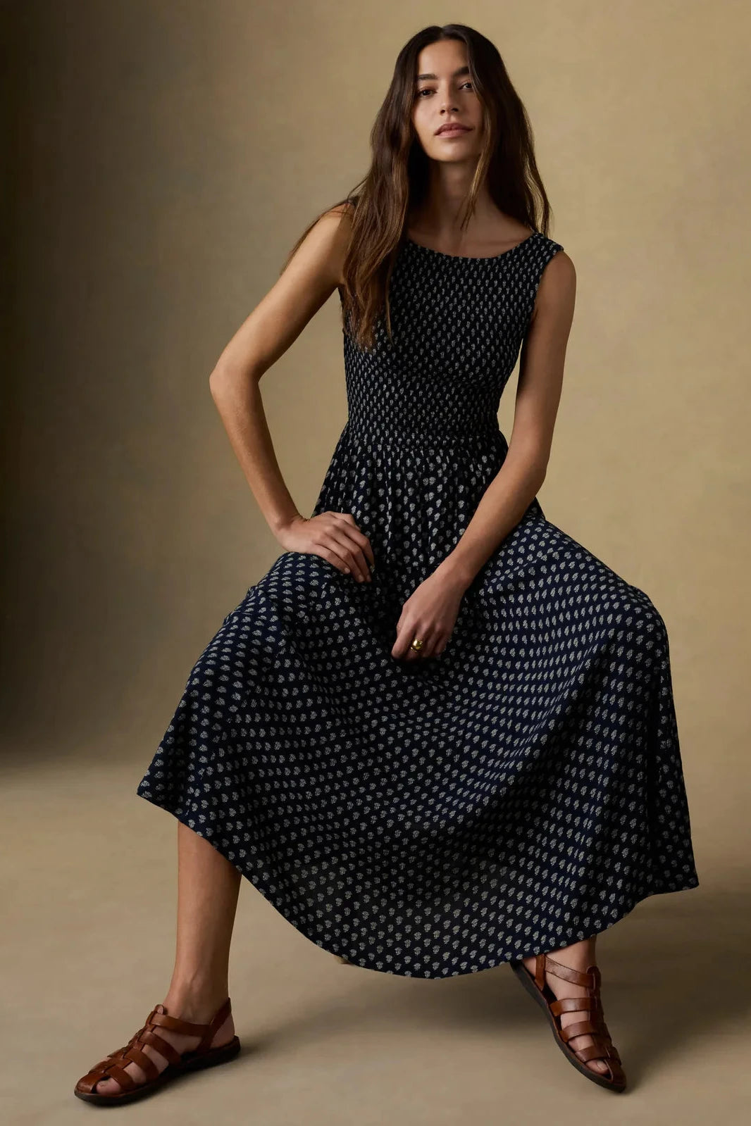 Woman wearing a black polka dot dress sitting against a beige background