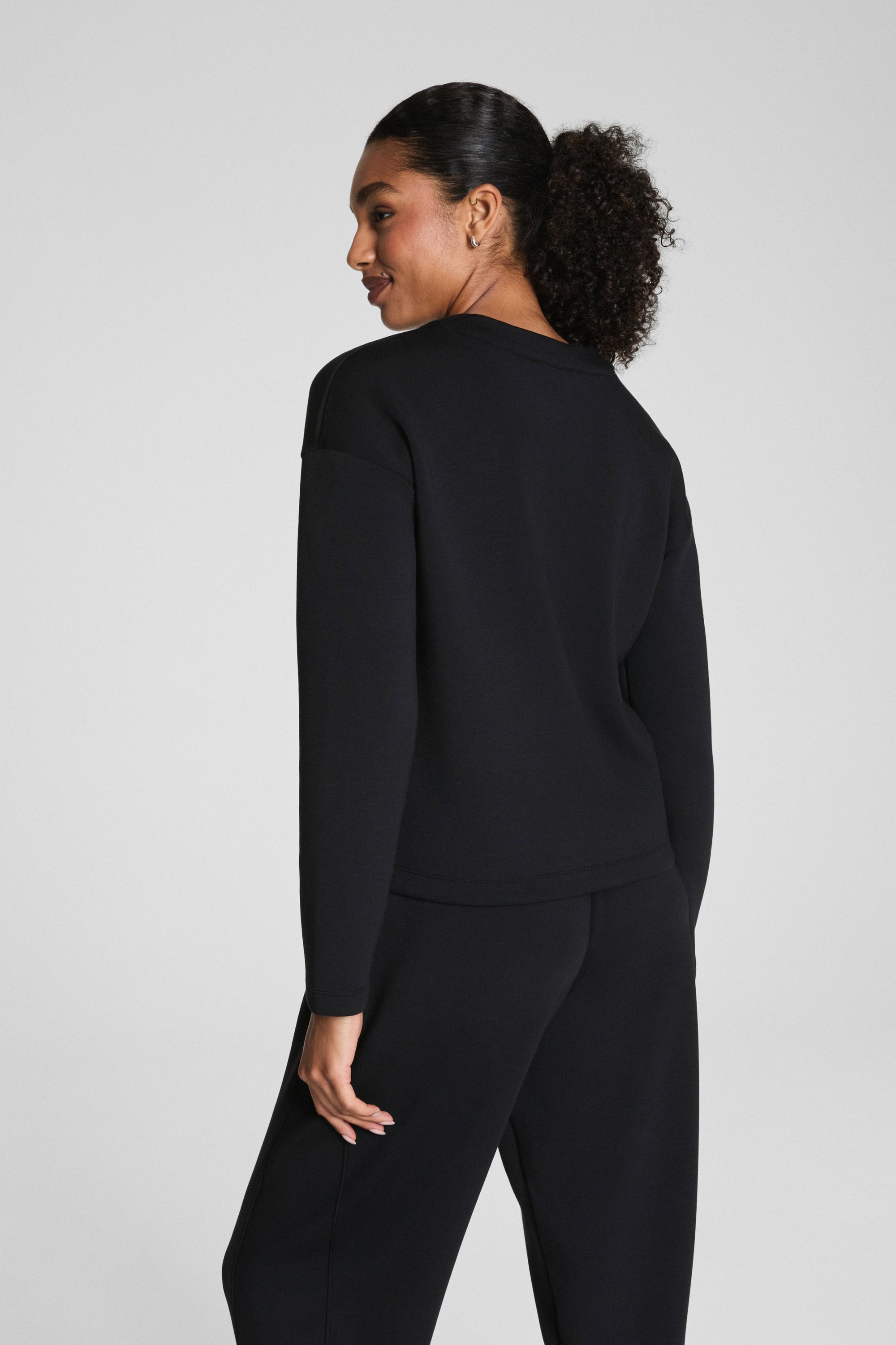 Person wearing a black outfit on a plain background