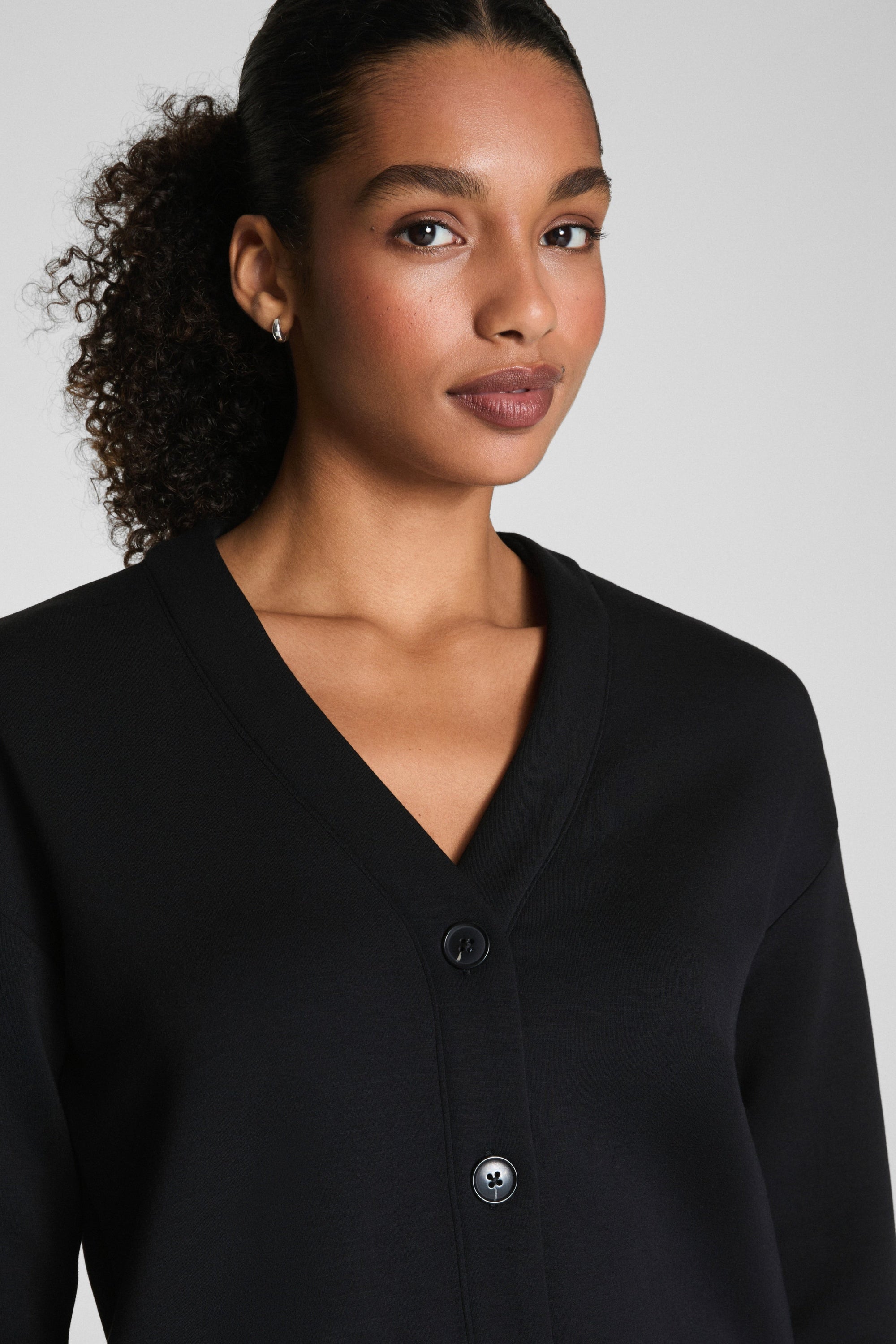 Woman wearing a black cardigan against a plain background