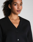 Woman wearing a black cardigan against a plain background